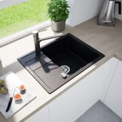 Nowoczesny zlew z deską do krojenia, na której leżą figi i nóż. Obok butelka oliwy i roślina.