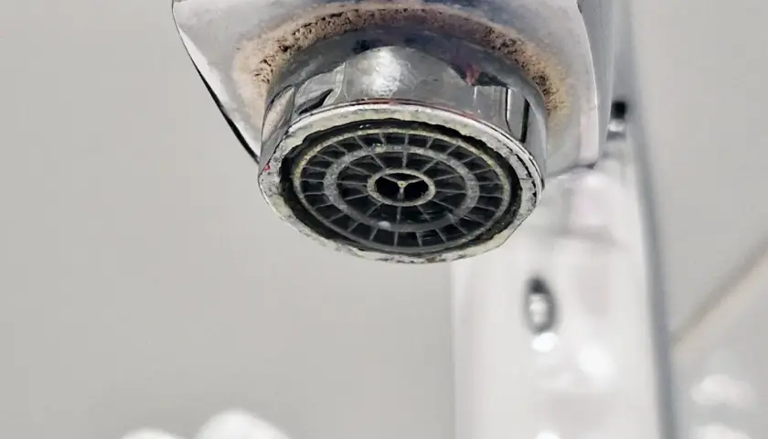 Zakamieniony perlator kranu z widocznym osadem wapiennym.