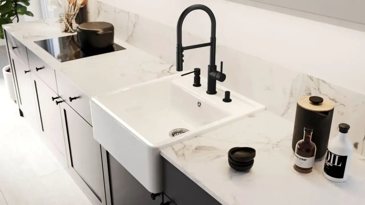 Biały, ceramiczny zlew bez ociekacza z czarną baterią i dozownikiem na blacie z marmuru.